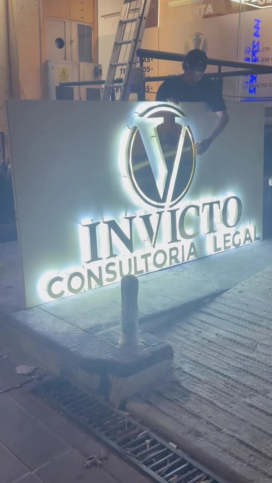 Letrero iluminado de Invicto Consultoría Legal por la noche